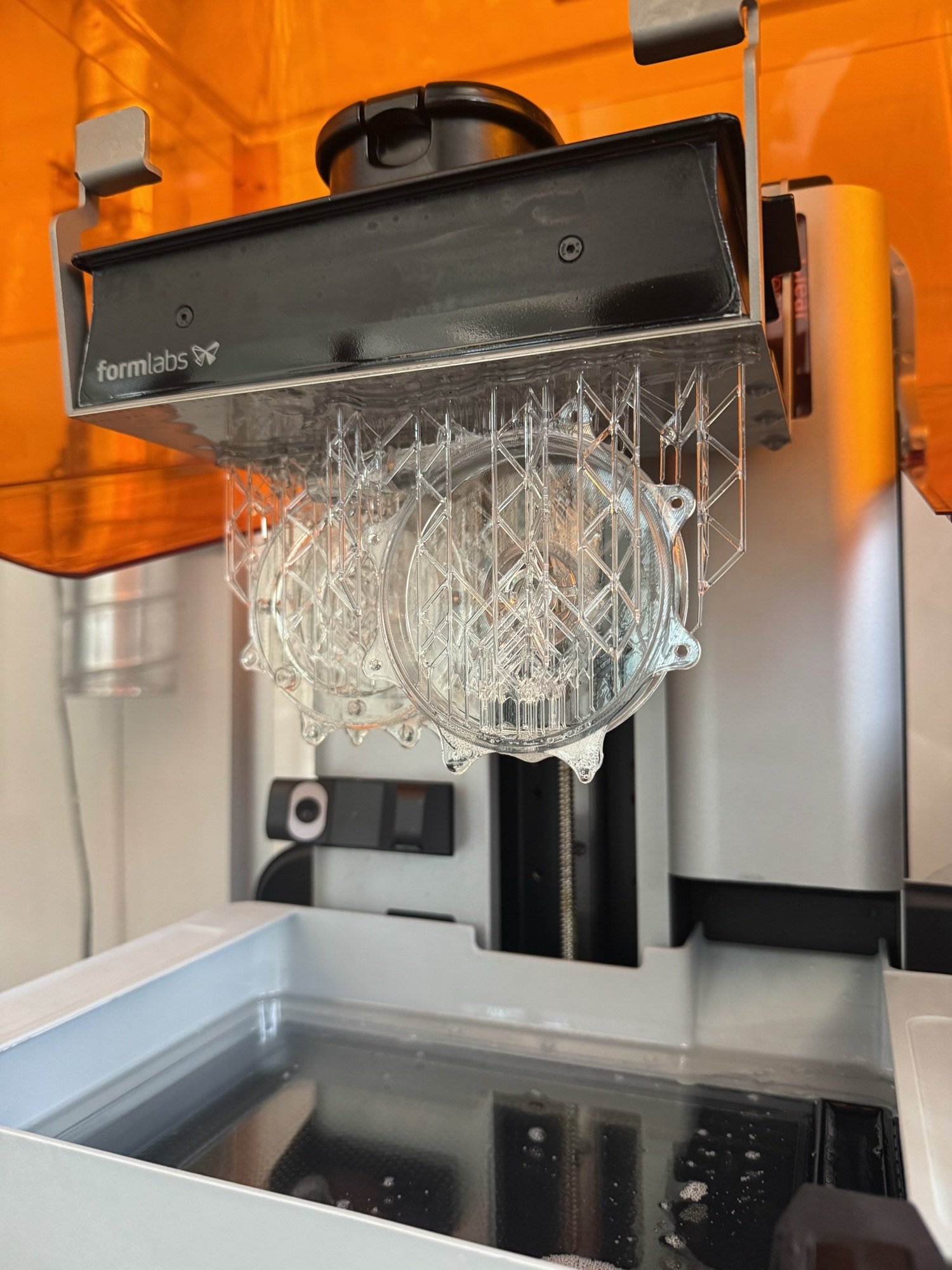 Clear resin volute and impeller parts on the Formlabs build platform, still on supports